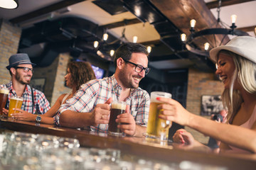 Wall Mural - Happy friends having fun at bar - Young trendy people drinking beer and laughing together