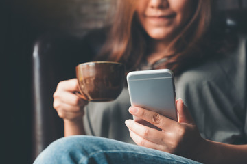 Canvas Print - Closeup image of a woman holding , using and touching a smart phone while drinking coffee