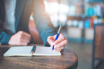 Business woman hand  writing on a notepad with a pen in the office.