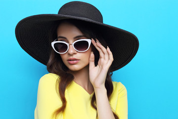 Fashion portrait of young woman wearing hat and sunglasses.