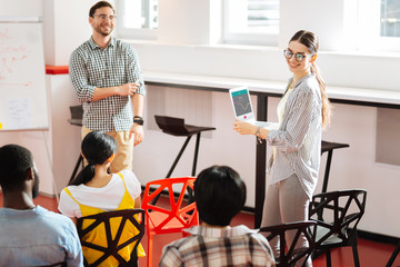 interesting session. positive young girl holding a laptop and smiling to the audience while taking p