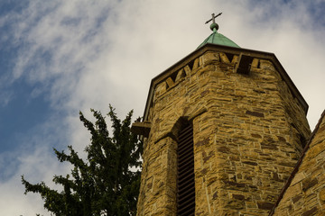 An old church tower below a cloudy summer sky