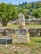 Headless sculpture at the Ancient Agora of Athens with tourists walking over the north slope of the Athenian Acropolis in background. Attica region, Greece.