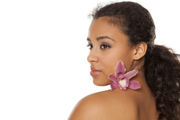 Wall Mural - portrait of young beautiful dark-skinned woman with orchid on a white background