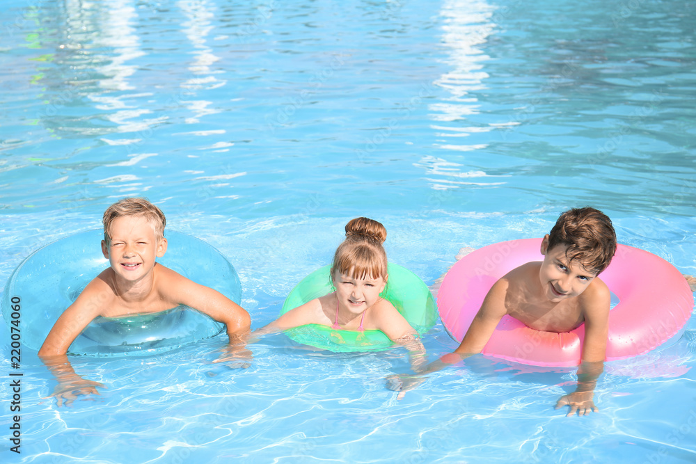 Cute children swimming in pool on summer day
