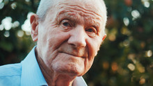 Very Old Man Portrait With Emotions. Grandfather Is Smiling And Looking To Camera. Portrait: Aged, Elderly, Senior. Close-up Of Old Man Sitting Alone Outdoors.