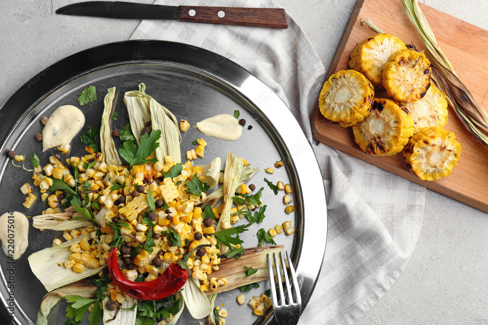 Tasty grilled corns with sauce on metal plate