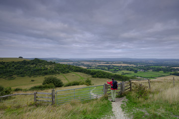 Wall Mural - A middle aged male walker with backpack admiring the view from Beacon Hill and Harting Down in the South Downs National Park, Hampshire, UK