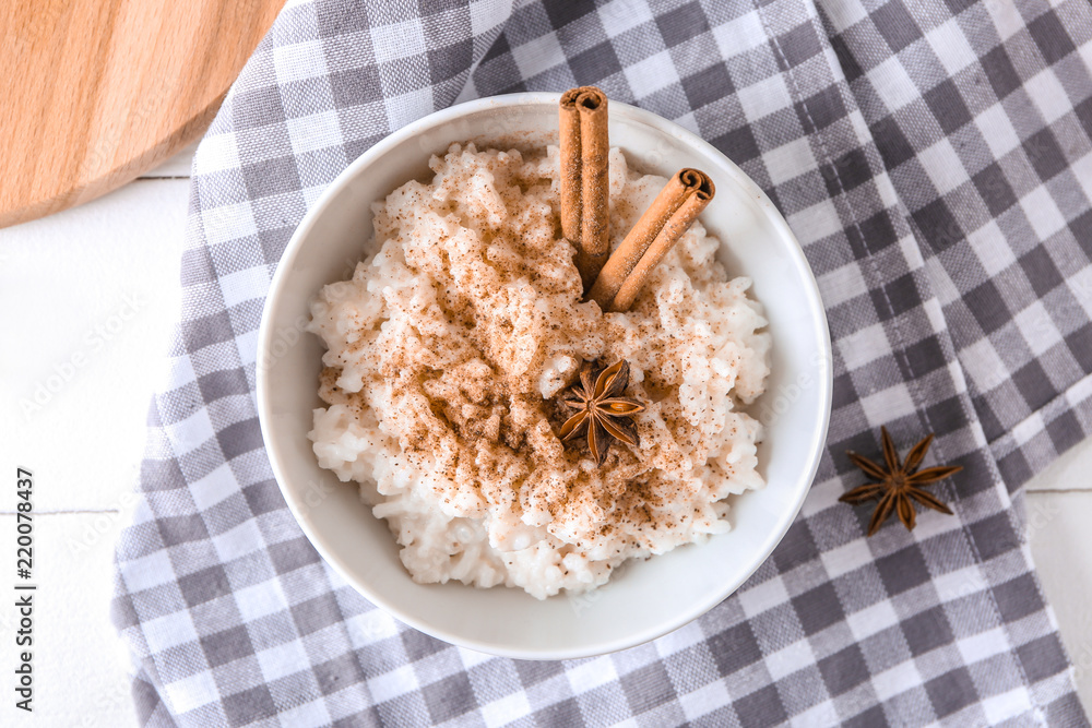 Bowl with delicious rice pudding and cinnamon powder on table