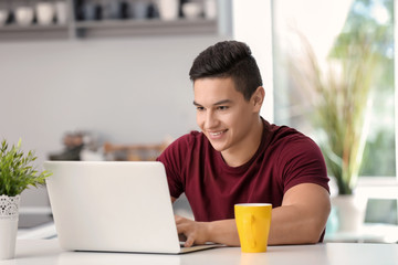 Young freelancer working on laptop in kitchen