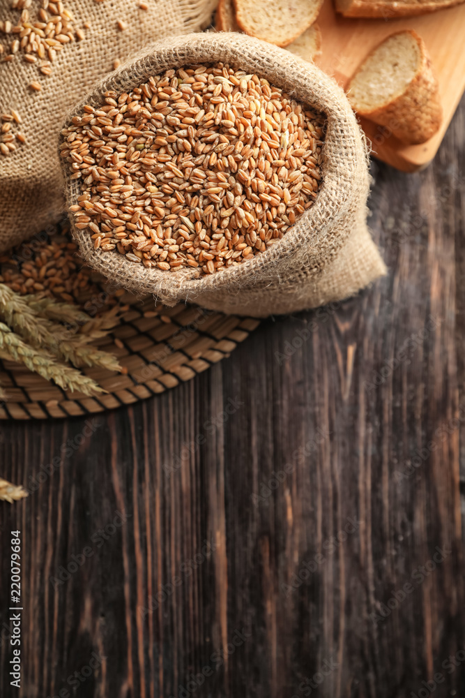 Bag with raw wheat on wooden table