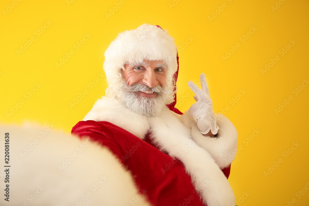 Santa Claus taking selfie on color background