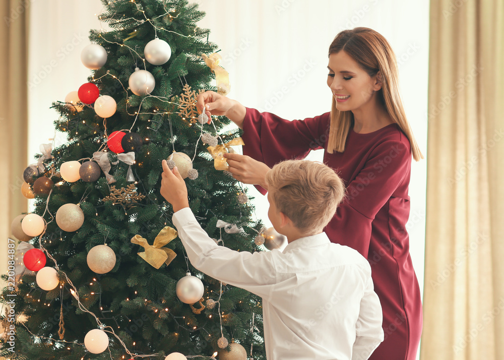 Mother and son decorating beautiful Christmas tree in room