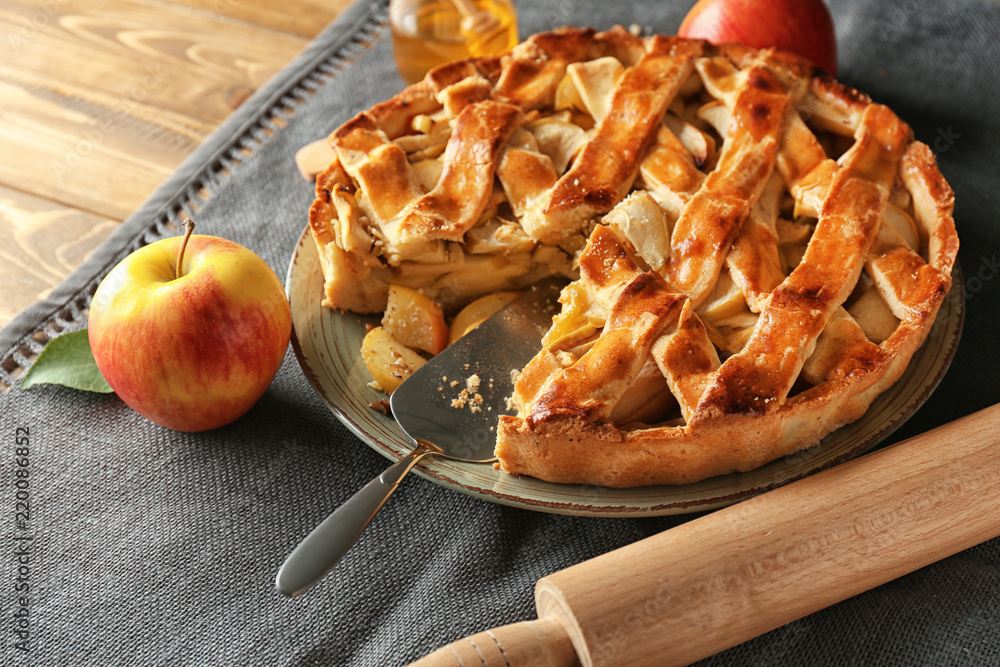 Plate with delicious apple pie on wooden table