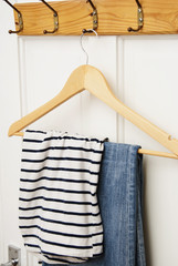 Casual clothes on wooden hanger on white door with copy paste. Jeans and tshirt on clothes hanger. Fashion.