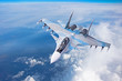 Combat fighter jet on a military mission with weapons - rockets, bombs, weapons on wings flies high in the sky above the clouds.