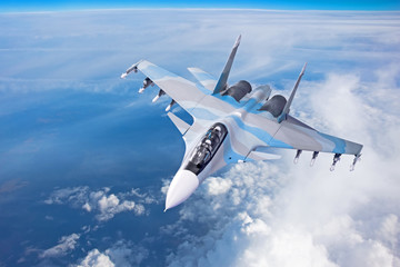 Wall Mural - Combat fighter jet on a military mission with weapons - rockets, bombs, weapons on wings flies high in the sky above the clouds.