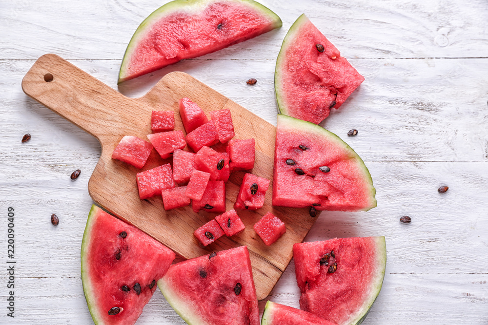 Pieces of ripe watermelon with cutting board on white table