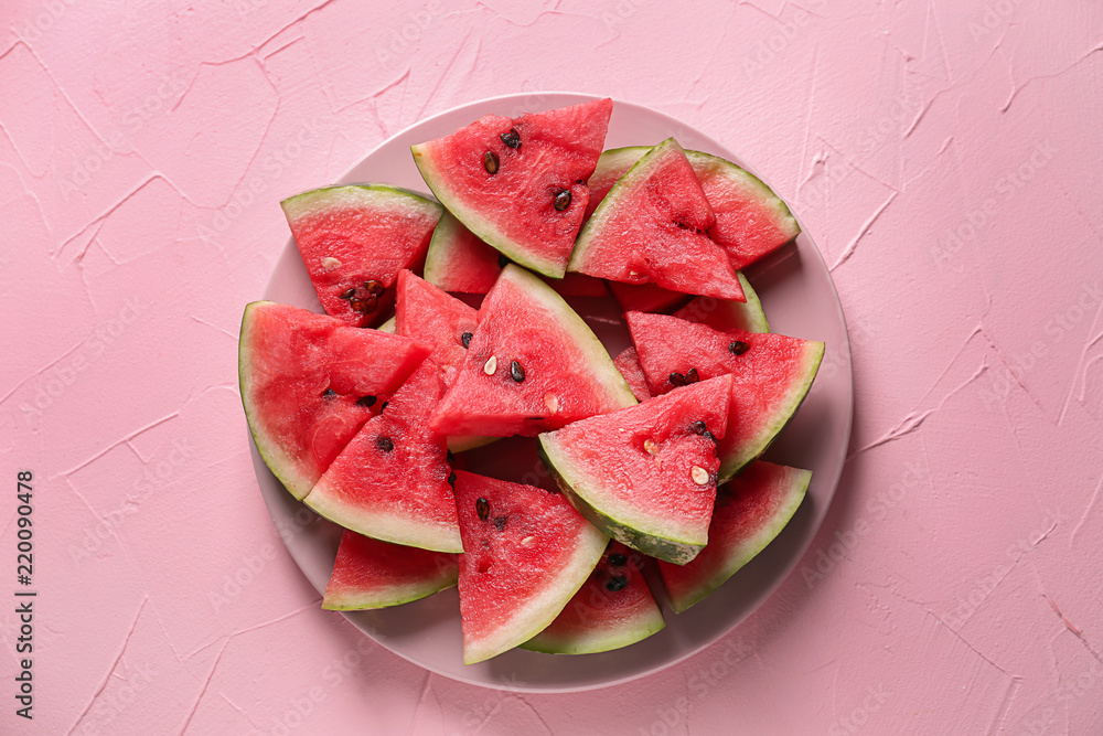Plate with slices of ripe watermelon on color background