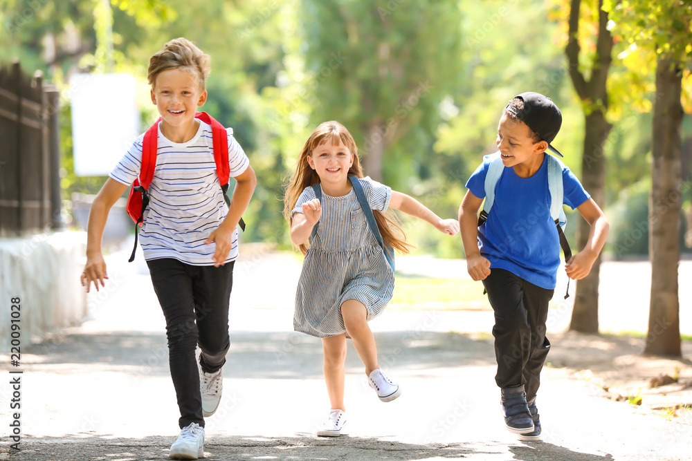 Cute little schoolchildren running outdoors