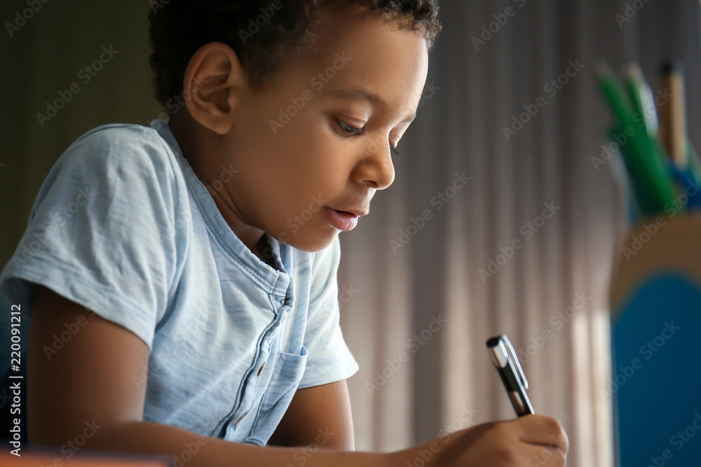 Cute African-American boy doing his lessons at home