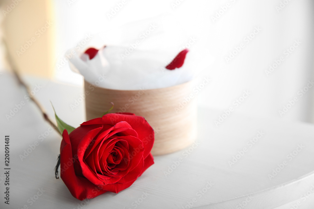 Beautiful red rose and gift box on white table