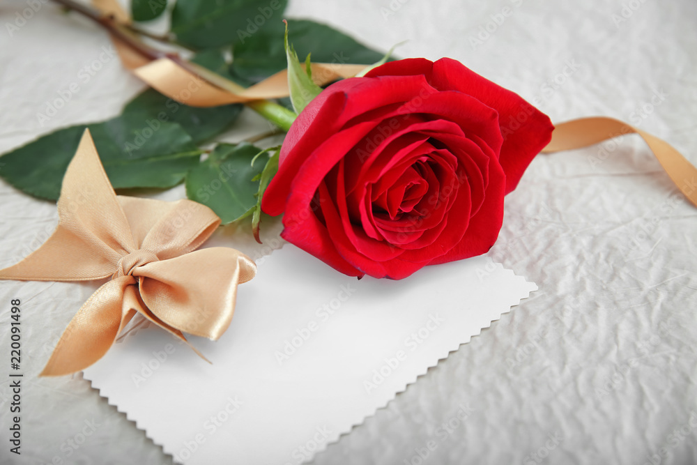 Beautiful red rose and blank card on light table