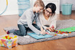 © Photographee.eu - Mother and autistic boy drawing a picture on the floor at home