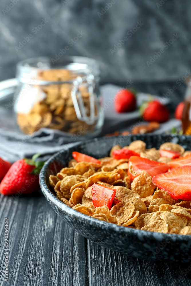 Plate with tasty corn flakes and strawberry on dark table