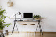 © Photographee.eu - Two hairpin stools placed by black desk with metal lamp, fresh plant and mockup monitor in real photo of white living room interior with empty wall