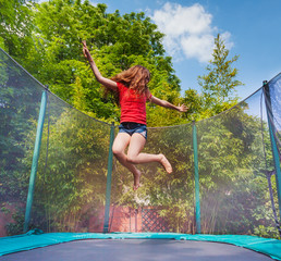 Wall Mural - Active girl jumping on trampoline outdoors