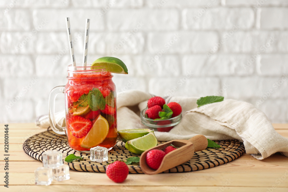 Mason jar of fresh strawberry mojito on wicker mat