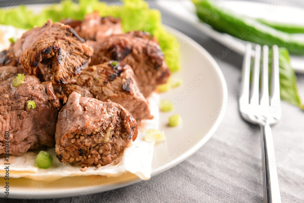 Plate with delicious shish kebab on table, closeup