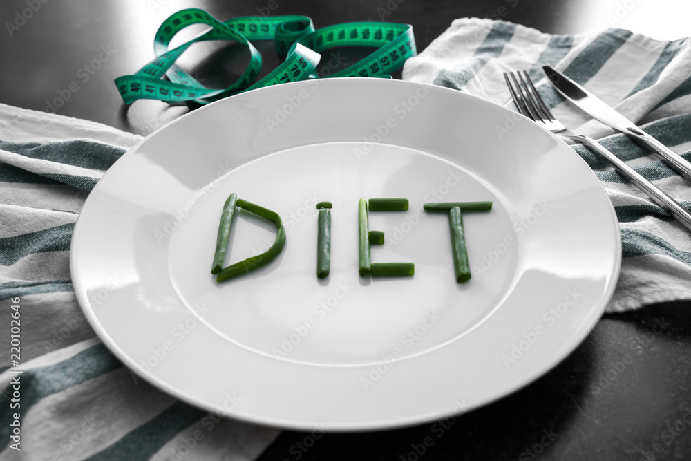 Plate with word "Diet" and measuring tape on table