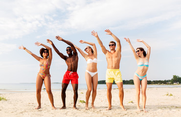 Wall Mural - friendship, summer holidays and people concept - group of happy friends having fun on beach