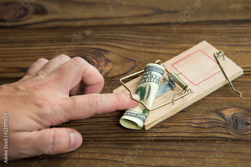Fotografía A man's hand got caught in a mousetrap with bait money dollar bills