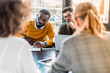 © LIGHTFIELD STUDIOS - multicultural businesspeople sitting at table in office