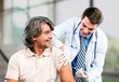 © BillionPhotos.com - Handsome doctor making vaccination to male patient on background