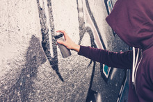 Graffiti Artist With Aerosol Spray Bottle Near The Wall