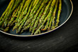 delicious and juicy green asparagus in a pan on an old wooden black table
