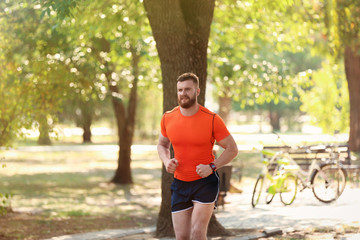 Young man running in park on sunny day