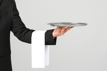 Canvas Print - Waiter holding metal tray on light background