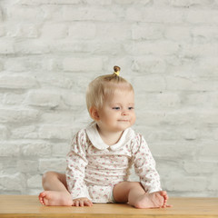 Wall Mural - Portrait of a cute baby girl sitting in the room