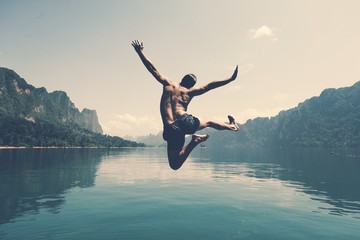 man jumping with joy by a lake