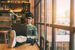 Asian man doing freelance work sitting out on a laptop computer connected to 4G Internet with a smart phone casual. By the window of a vintage coffee shop.