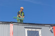 © Makeev Petr - Worker at the construction site cleans the roof of the water with a brush