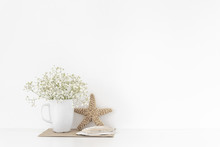 Background With Stationary, Seashells, Sea Star, Bouquet Of White Flowers In Mug On White Wall Background, Cute Soft Home Decor. Copy Space For Text. Empty Space For Lettering. Good Buy Summer
