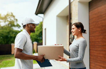 Courier Delivery. Man Delivering Package To Woman At Home