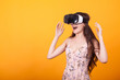© DC Studio - Girl wearing a VR headset and experiencing virtual reality, technology and innovation concept in studio over yellow background.Much gesticulating hands
