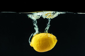 Poster - fresh yellow lemon in water splash on black background